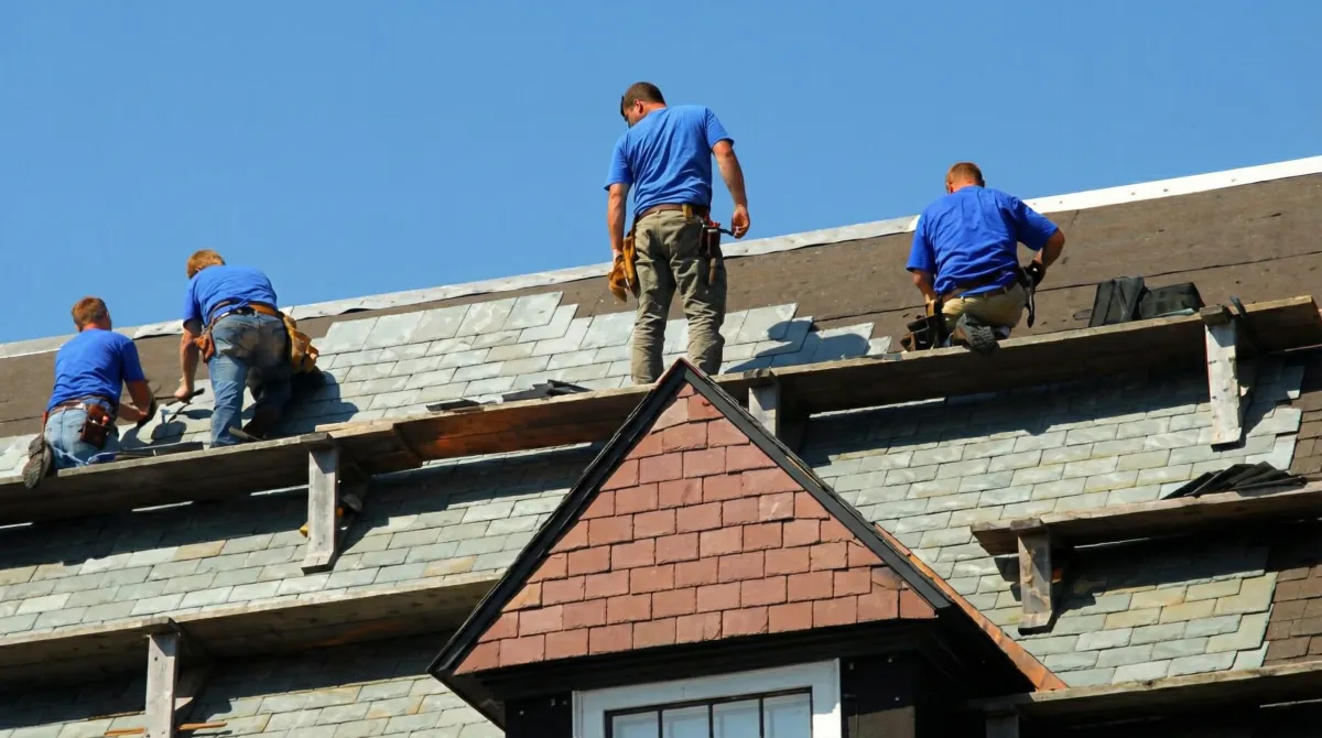 Roof replacement in progress with a team of professional contractors installing new shingles on a residential home in Kansas City, KS